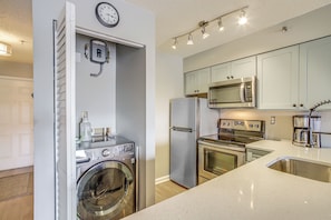 A compact kitchen with a washing machine, refrigerator, microwave, and oven.