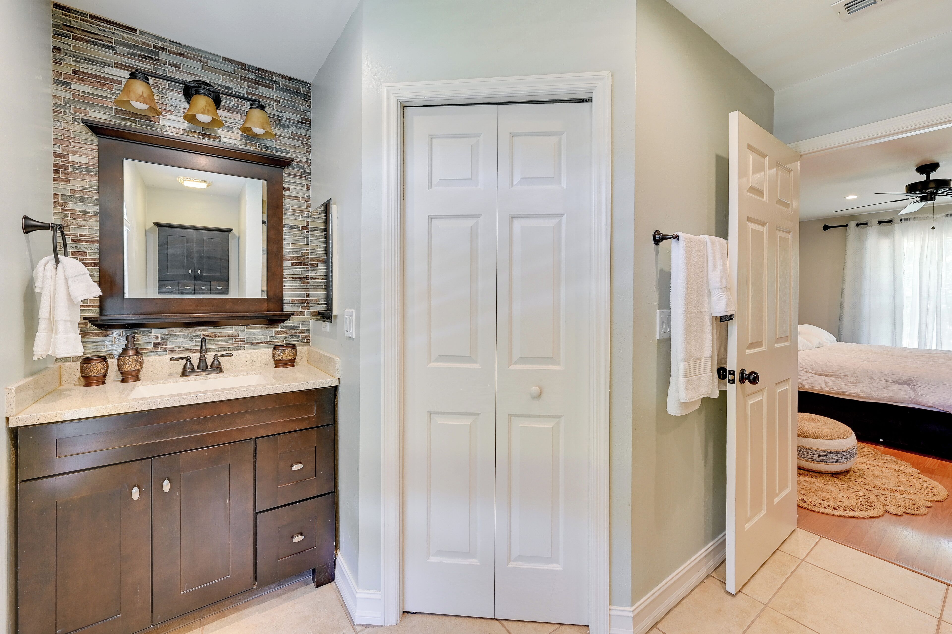 Une salle de bain avec un grand miroir, un meuble-lavabo en bois foncé et une porte blanche.