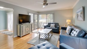 Un salon moderne avec un téléviseur à écran plat, un ventilateur de plafond, un canapé bleu et une table basse.