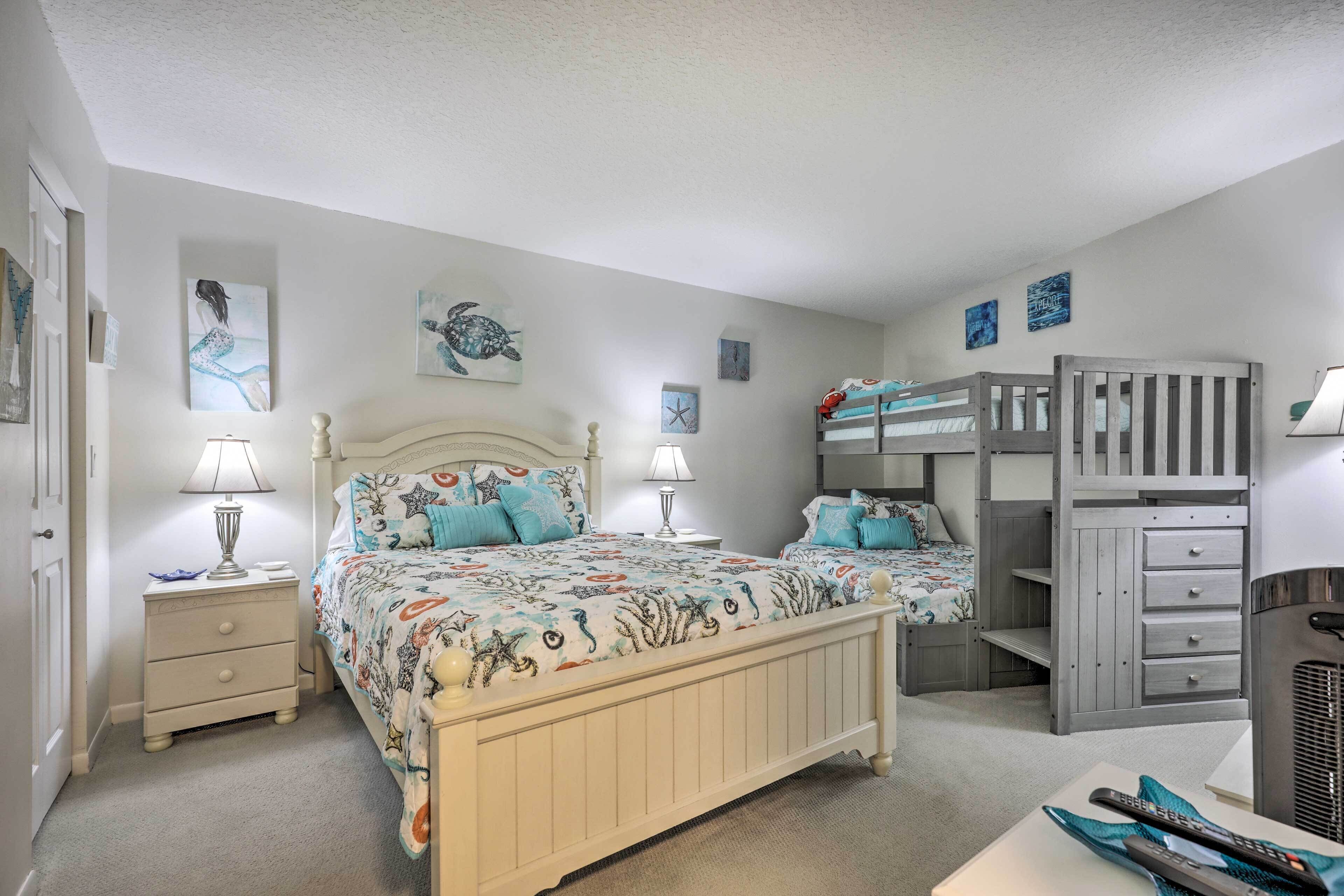 A bedroom with two beds, a bunk bed, a nightstand, and a dresser.