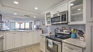 A modern kitchen with white cabinets, a stainless steel oven, a microwave, and a tiled backsplash. - St Augustine Condo w/ Direct Ocean Access! (St. Augustine)
