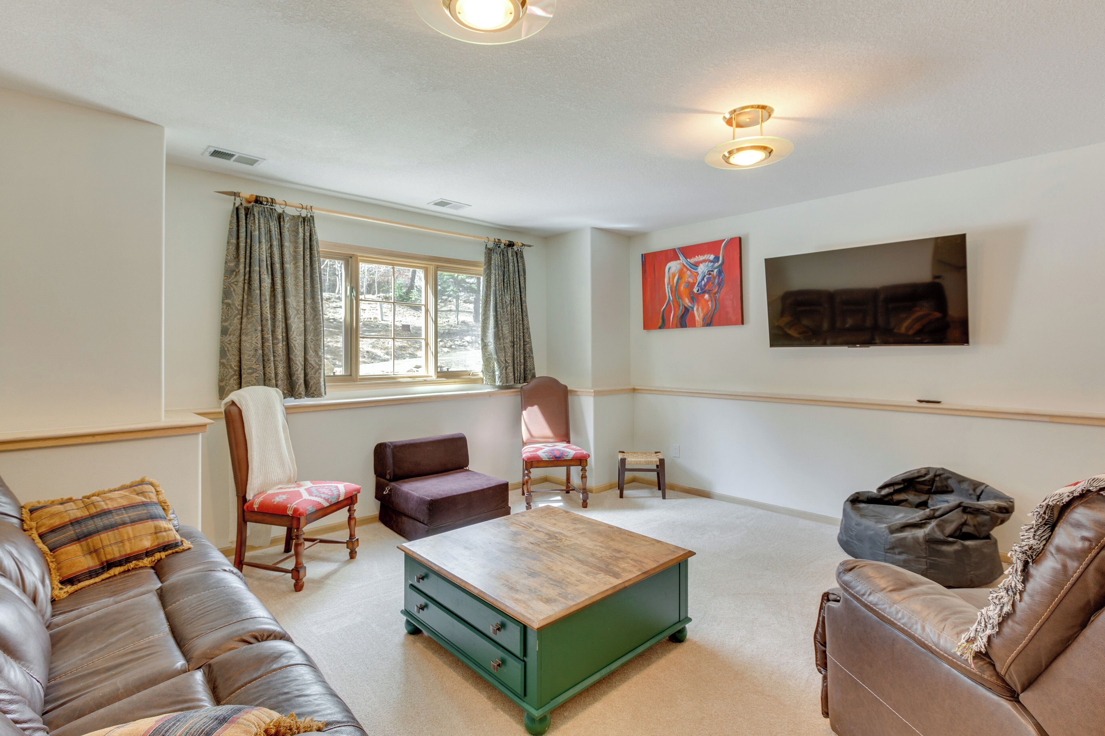 A living room with a green coffee table, leather sofas, and a television on the wall.
