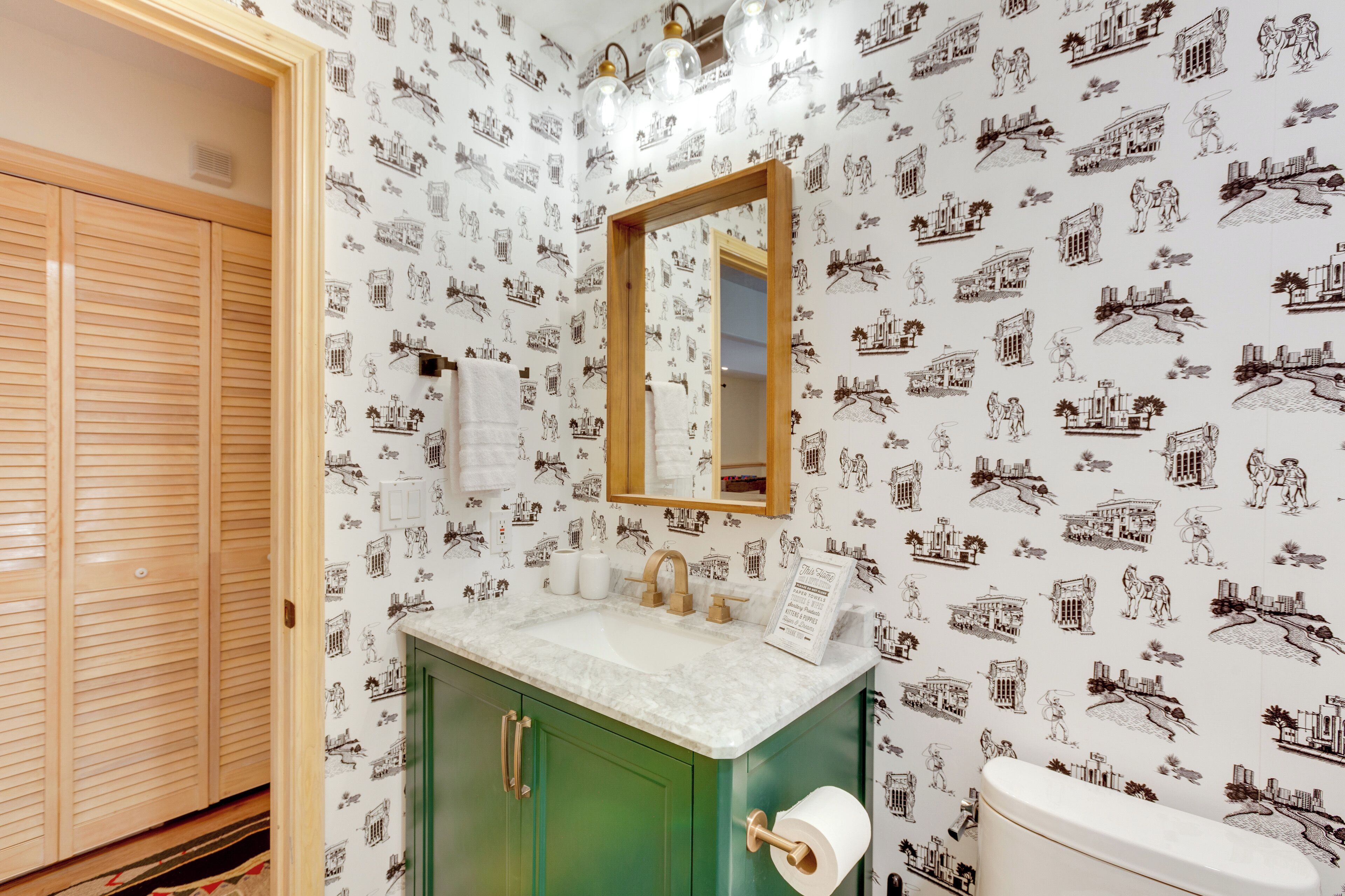 A bathroom with a green vanity, a white sink, a mirror, and a toilet.