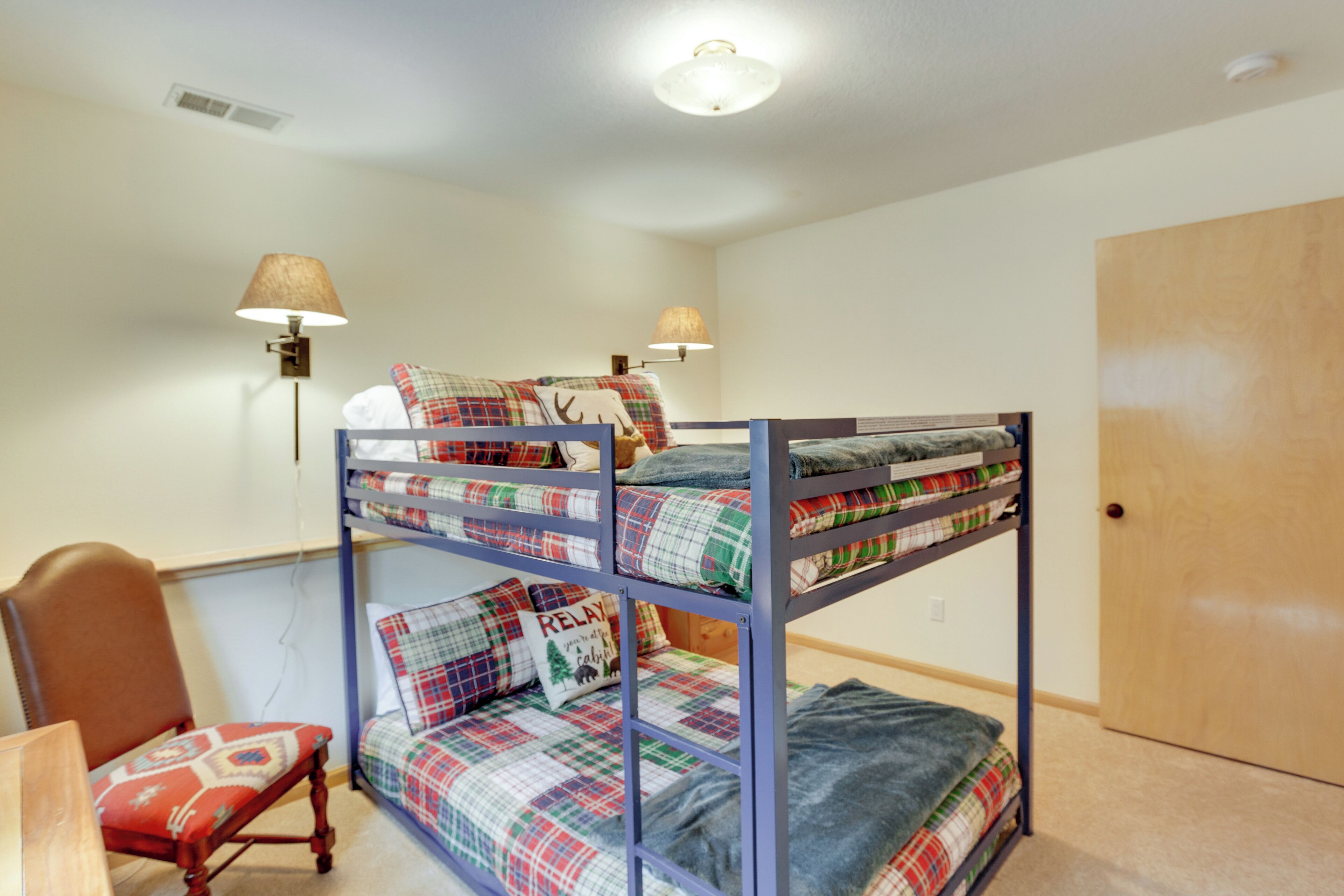 A bunk bed room with a chair and two wall lamps.
