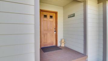 A wooden front door with a welcome mat and a small bear decoration.