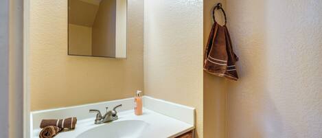 A bathroom with a white sink, a mirror, and a towel rack.