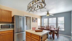A kitchen with wooden cabinets, stainless steel appliances, a dining area with a table and chairs, and a ceiling fan. - San Antonio Home w/ Private Hot Tub + Pool! (San Antonio)