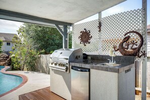 Cocina exterior con parrilla integrada, pileta y espacio de almacenamiento.