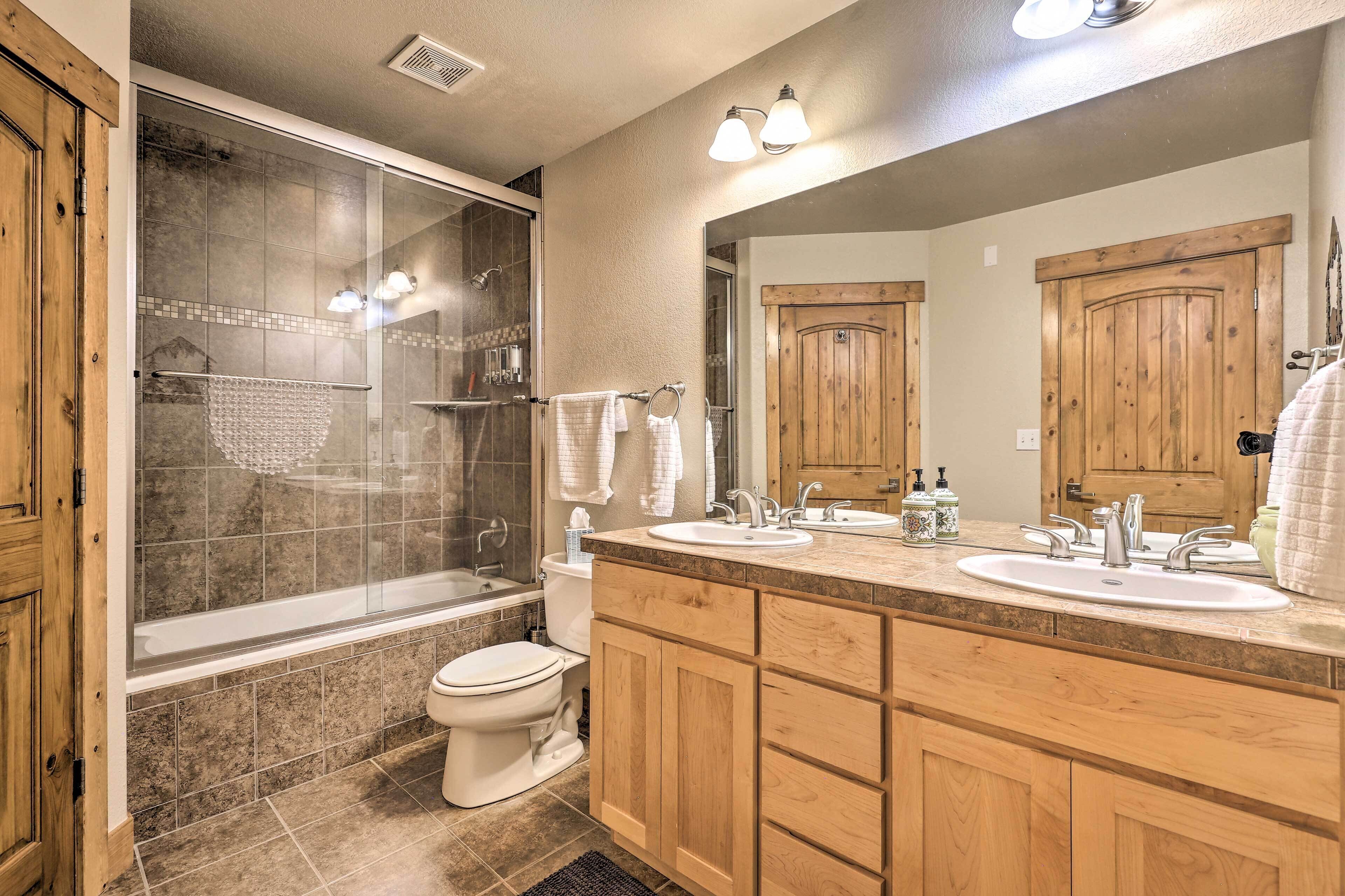 Un baño moderno con ducha envuelta en vidrio, lavamanos doble y muebles de madera.