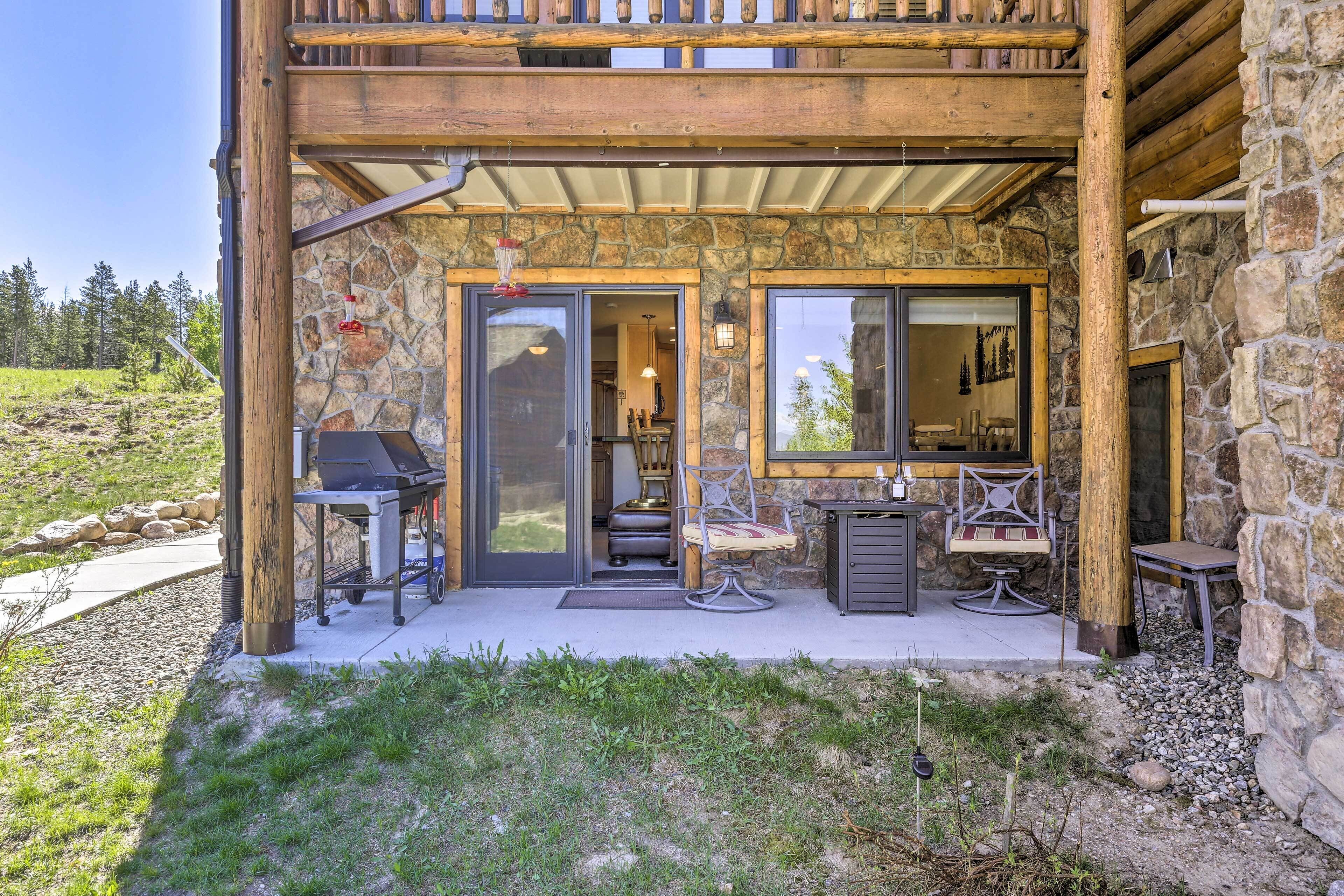 Ein zweistöckiges Steinhaus mit überdachter Terrasse, Außenplätzen und Grill.