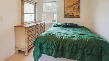 Un dormitorio con cama, cómoda, ventanas y un cuadro.