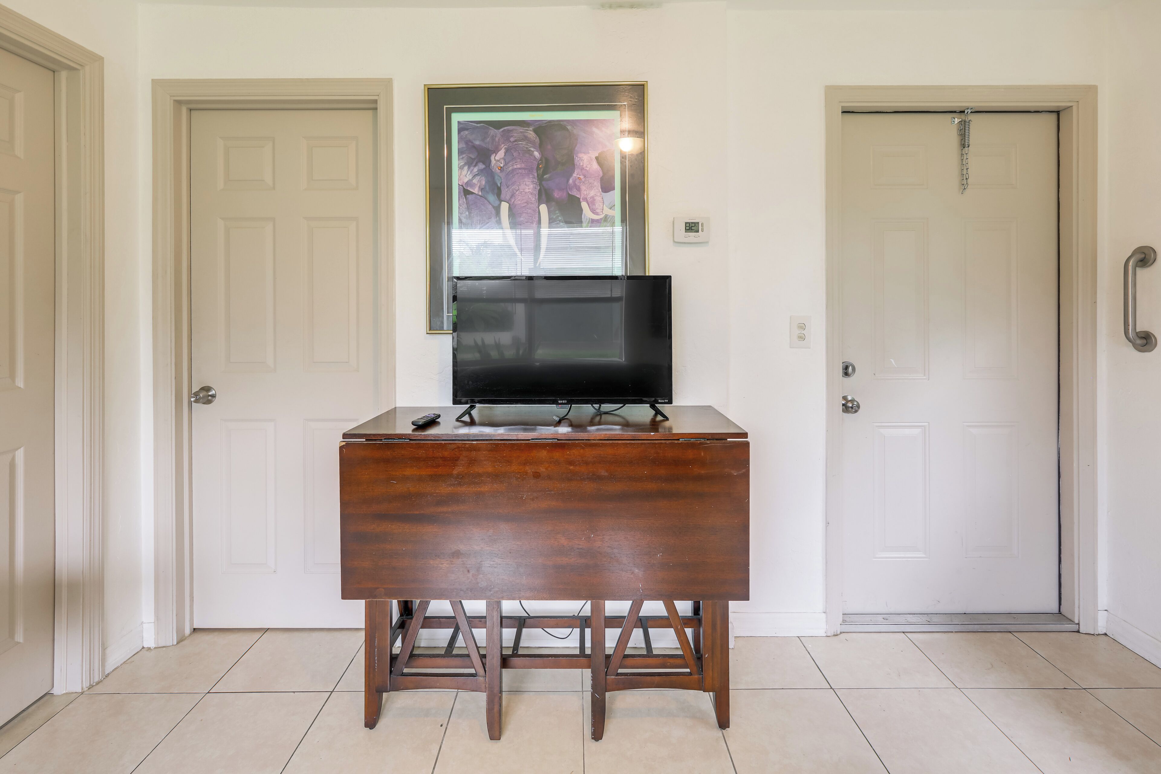 Una habitación con un escritorio de madera, un televisor y dos puertas.