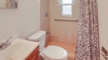 Un baño con inodoro, lavamanos y zona de ducha.