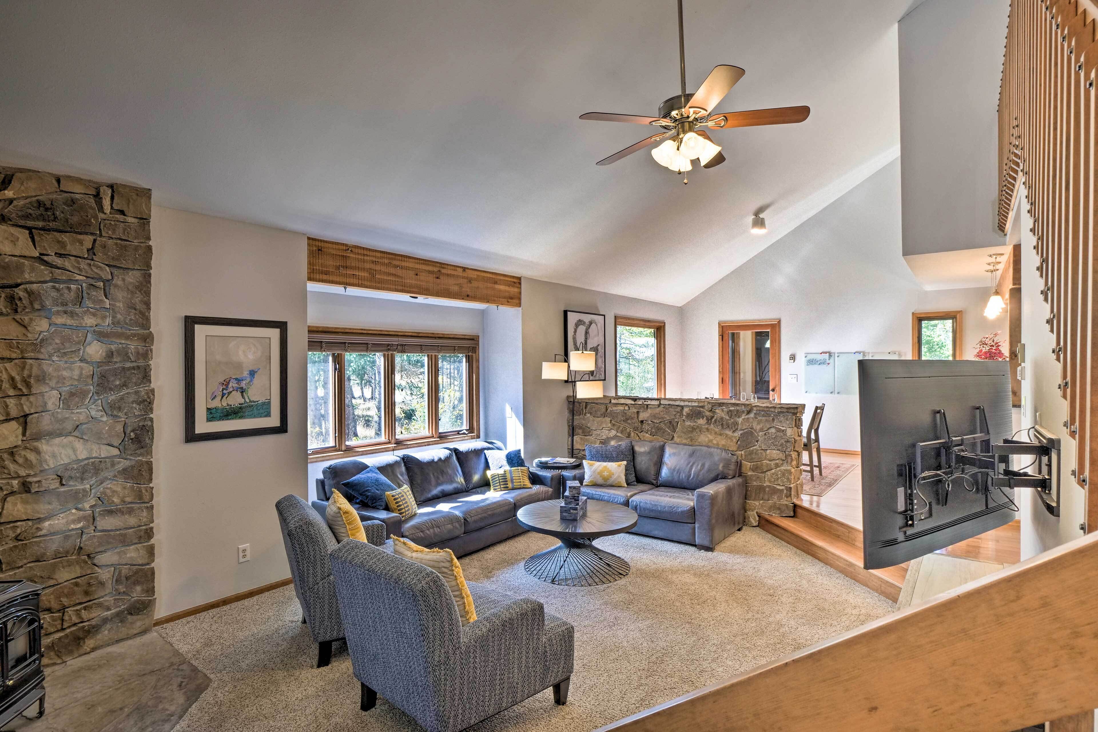 A spacious living room with a stone accent wall, a ceiling fan, and a large window providing natural light.