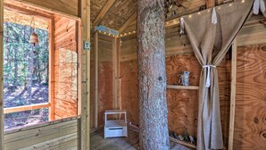 A wooden cabin interior with a large window, a wooden stool, and a tree trunk centerpiece. - 6 Mi to Breck Resort: Family Cabin w/ Game Room (Breckenridge)