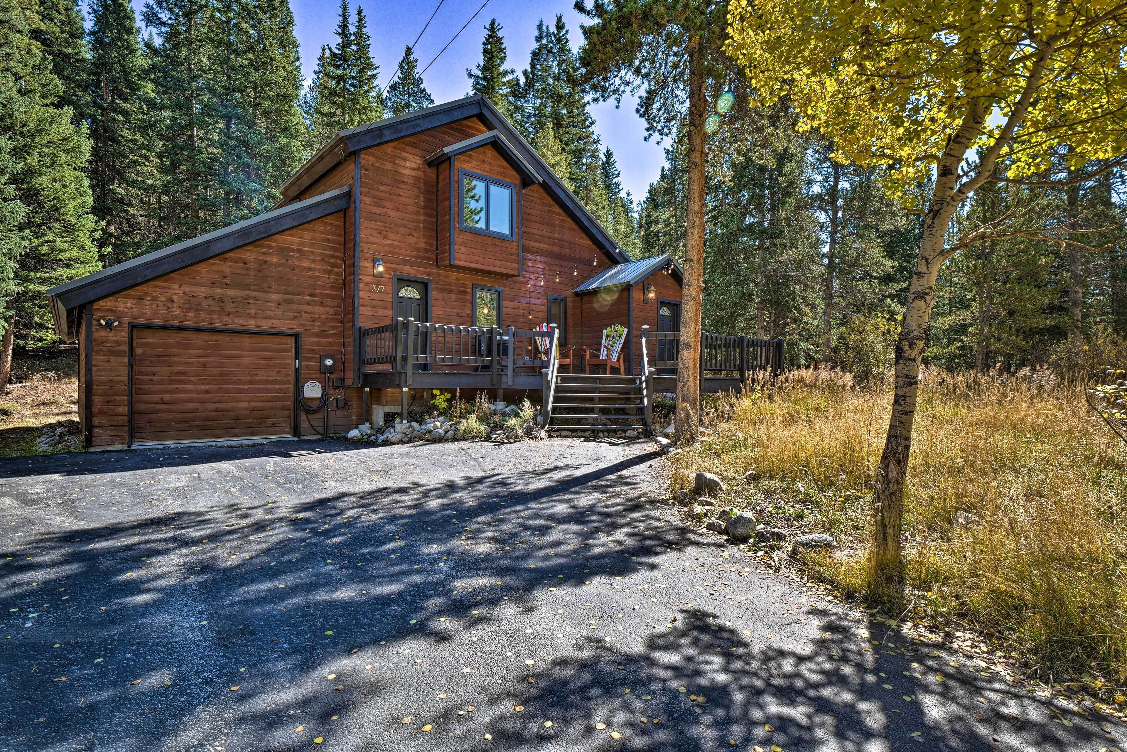 En træhytte med garage, overdækket veranda og trappe op til indgangen.