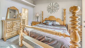 Un dormitorio con una cama de madera, un aparador, un espejo y un reloj de pared.
