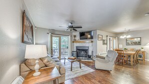 Una sala de estar con chimenea, comedor y ventilador de techo.