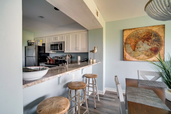 Una cucina moderna con mobili bianchi, un'isola grande con sgabelli e un'area pranzo con tavolo e sedie.
