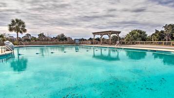 Ein klares Schwimmbecken mit einer Holzterrasse und einem Pavillon im Hintergrund.