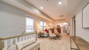 A spacious living room with a sofa, a dining table, and a kitchen in the background.
