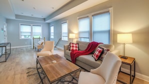 A spacious living room with a sofa, armchairs, a coffee table, and a lamp.
