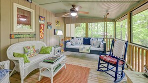 A cozy room with a white wicker sofa, a rocking chair, and a small table with books.