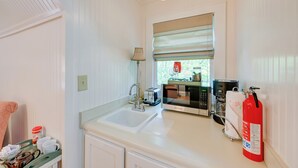 A kitchen with a white sink, a microwave, a toaster, and a fire extinguisher.