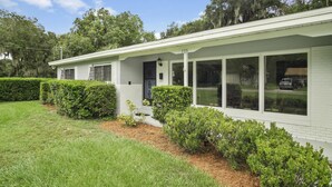A single-story house with a white exterior, large windows, and a black door.