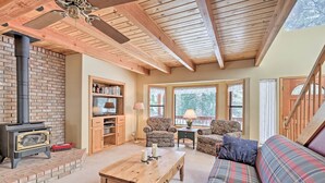 A cozy living room with a fireplace, wooden ceiling beams, and comfortable seating. - Near Bear Valley: Peaceful Arnold Home w/ Hot Tub (Arnold)