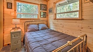 A wooden cabin bedroom with a bed, a nightstand, and framed pictures on the wall. - High Lakes Hideaway: La Pine Fishing Cabin! (La Pine)