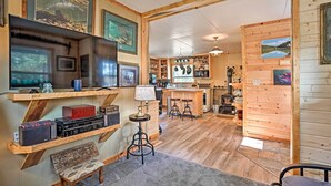 A cozy cabin interior with wooden walls, a large TV, and a bar area. - High Lakes Hideaway: La Pine Fishing Cabin! (La Pine)