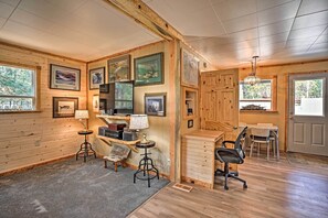 Un interior de cabaña acogedor con paredes de madera, un comedor y un espacio de trabajo con escritorio y sillas.