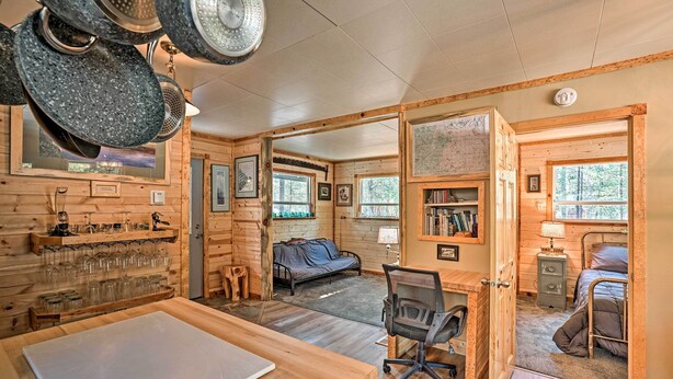 A cozy cabin with a wooden interior, a dining area, a workspace, and a bed. - High Lakes Hideaway: La Pine Fishing Cabin! (La Pine)