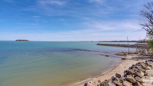 Une plage à l’eau claire, un rivage rocheux et une île qui se profile à l’horizon.