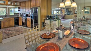 A modern kitchen with wooden cabinets, a dining area with glass tables, and a stone fireplace.