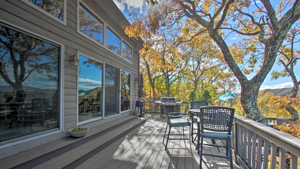 A wooden deck with outdoor furniture and a view of autumn trees.