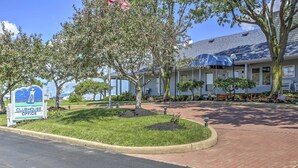 A Clubhouse Office building with a covered outdoor seating area, landscaped garden, and a clear blue sky. - Charming Port Clinton Condo w/ Community Amenities (Port Clinton)