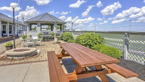 A patio area with a wooden table and benches, a gazebo, and a white fence. - Charming Port Clinton Condo w/ Community Amenities (Port Clinton)