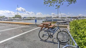 A bicycle parked near a wooden picnic table in a marina with boats in the background. - Charming Port Clinton Condo w/ Community Amenities (Port Clinton)