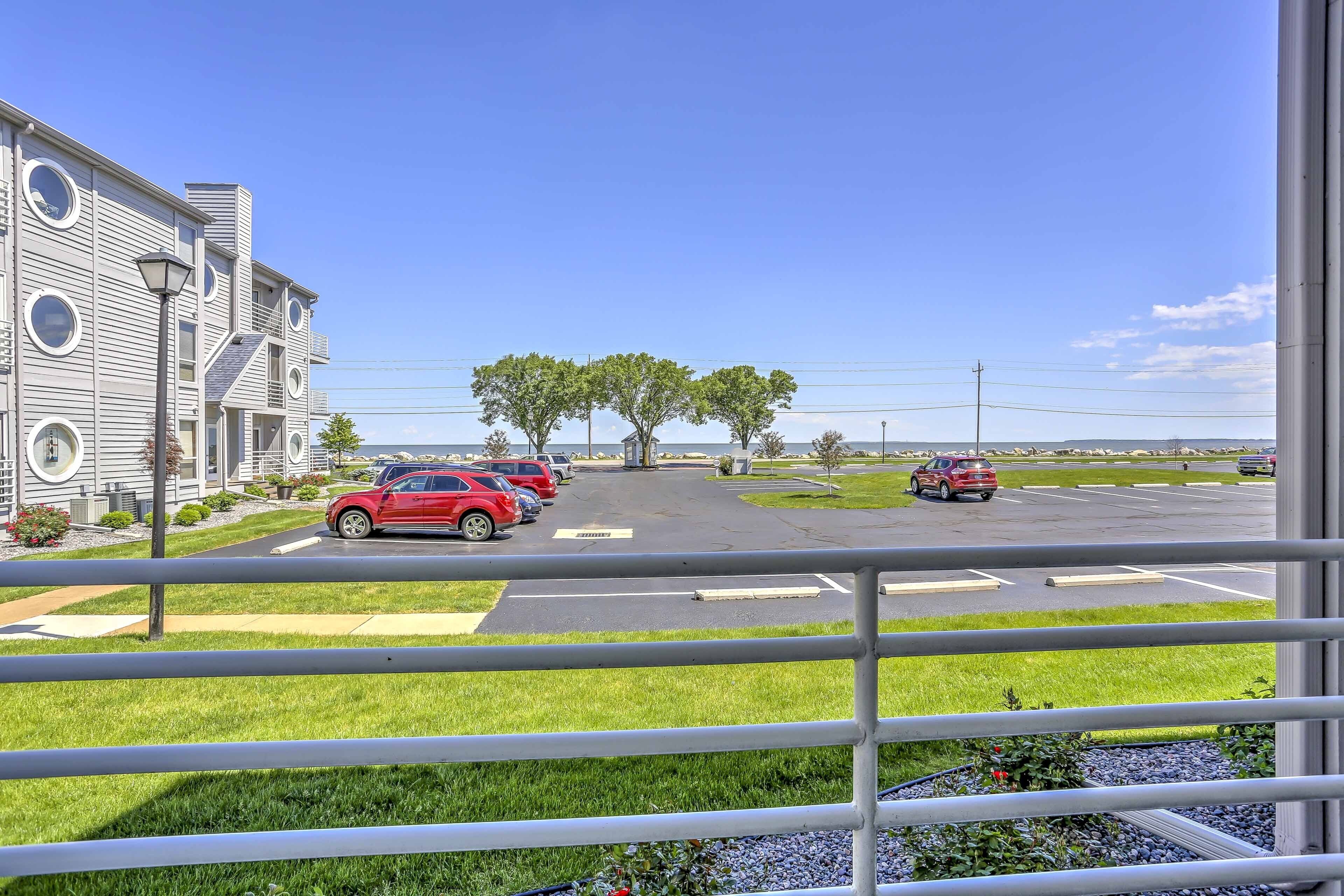 Une vue d’un parking avec plusieurs voitures, d’un bâtiment doté de fenêtres rondes et d’un ciel bleu dégagé.