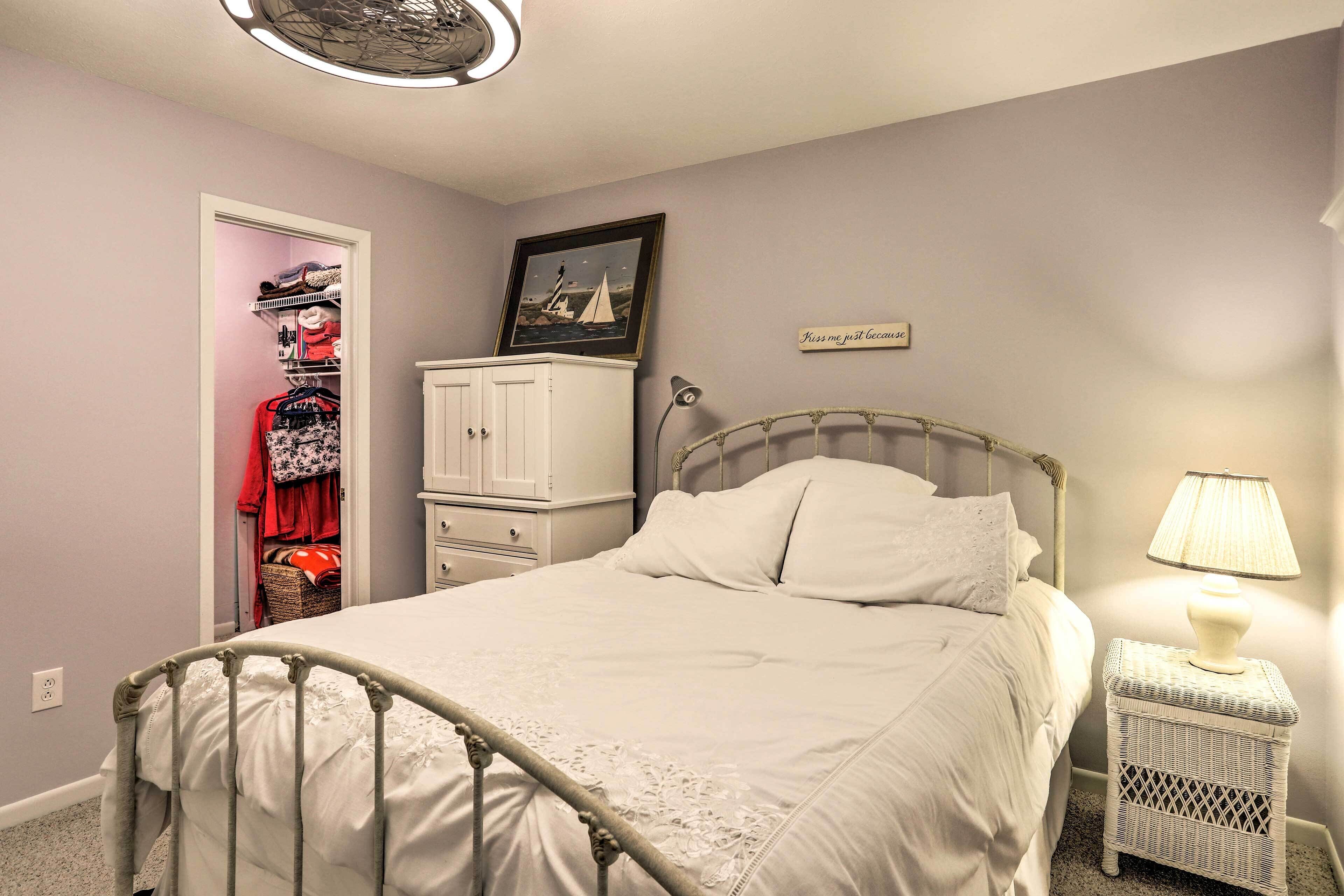A bedroom with a bed, a wardrobe, a bedside table with a lamp, and a framed picture on the wall.