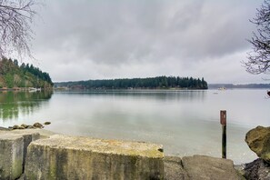 A calm lake with a dock and a signpost, surrounded by trees and a distant island.