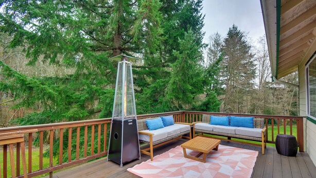 A wooden deck with a sofa, a table, and a heater. - Central 4-acre Cottage w/ Deck: Walk to Bay! (Bainbridge Island)