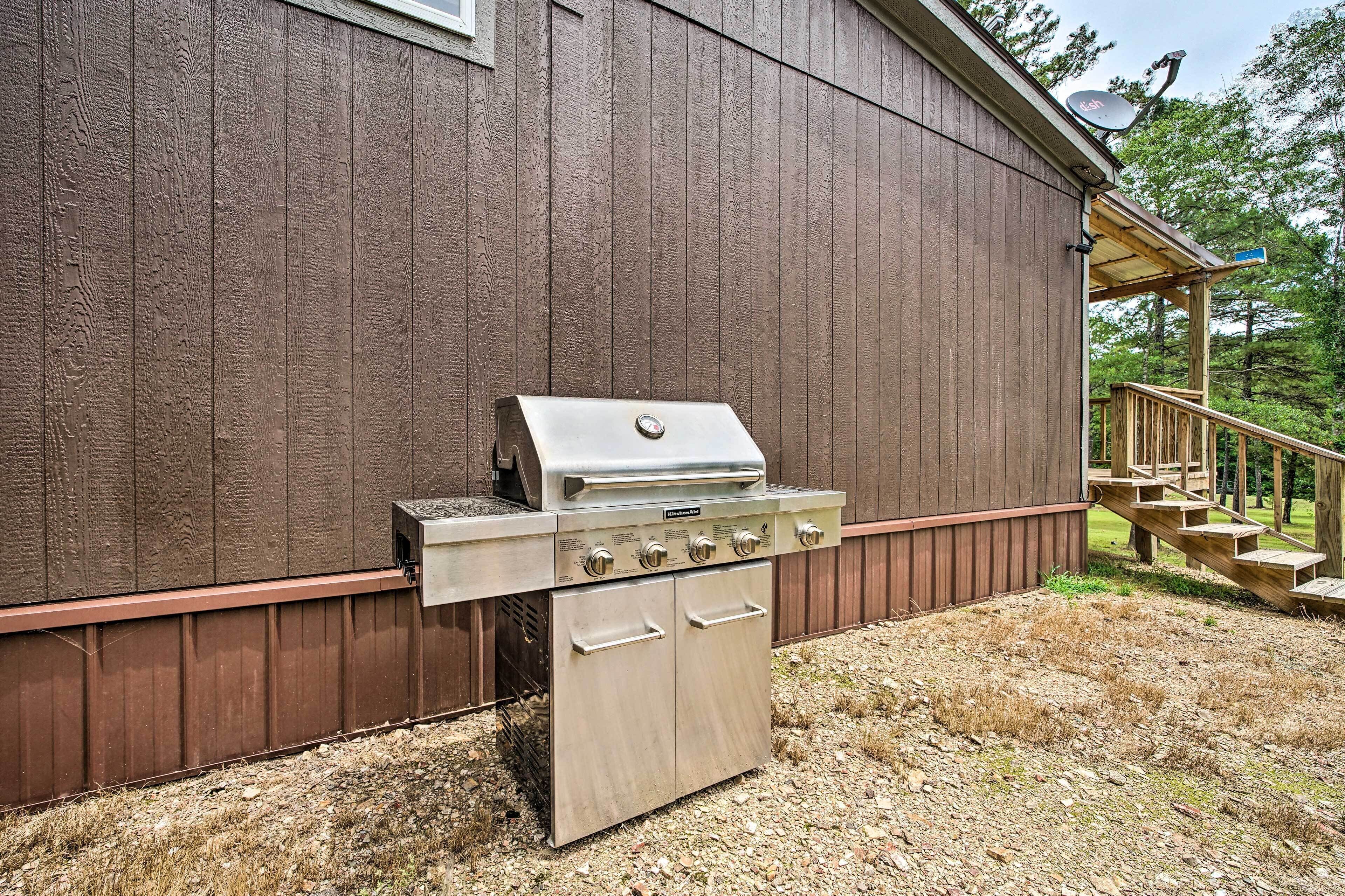 A stainless steel grill attached to a wooden building with a metal door and a small porch with steps.