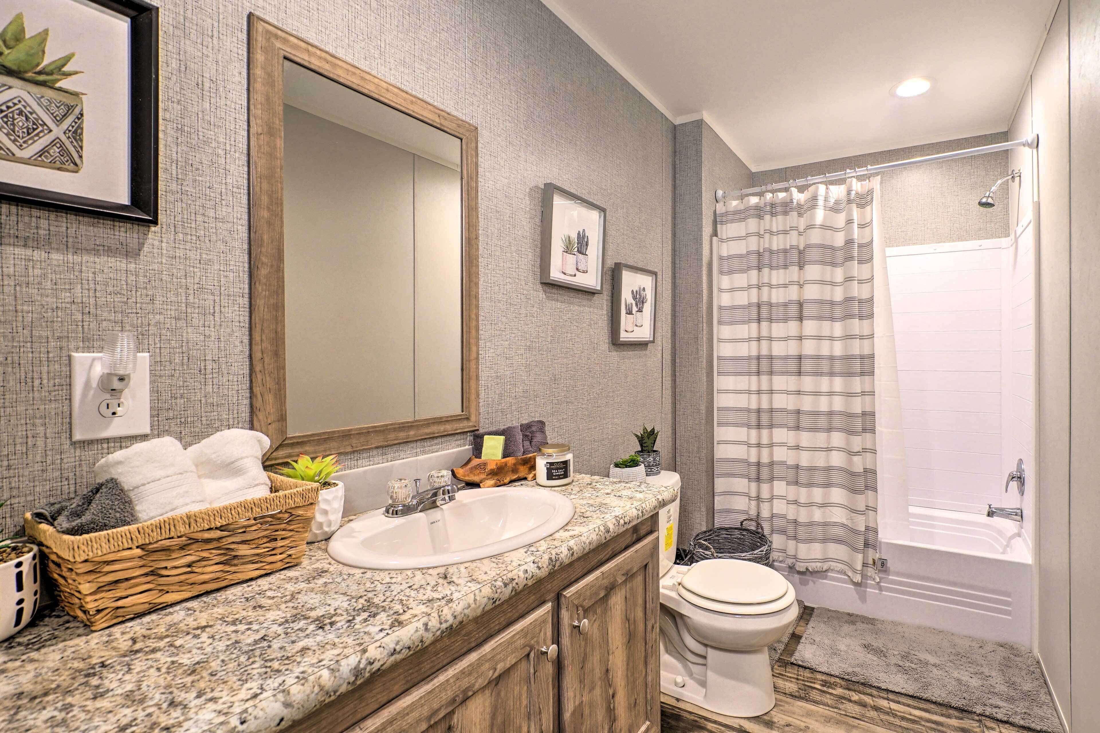 Une salle de bain avec un grand miroir, un lavabo, des toilettes et un espace douche.