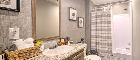 Une salle de bain avec un grand miroir, un lavabo, des toilettes et un espace douche.