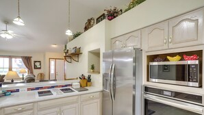 Una cocina moderna con armarios blancos, un refrigerador de acero inoxidable, un microondas y un horno.