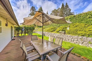 Eine Terrasse mit Tisch und Stühlen, eine Pergola mit Netzvorzelt und eine Steinmauer im Hintergrund.