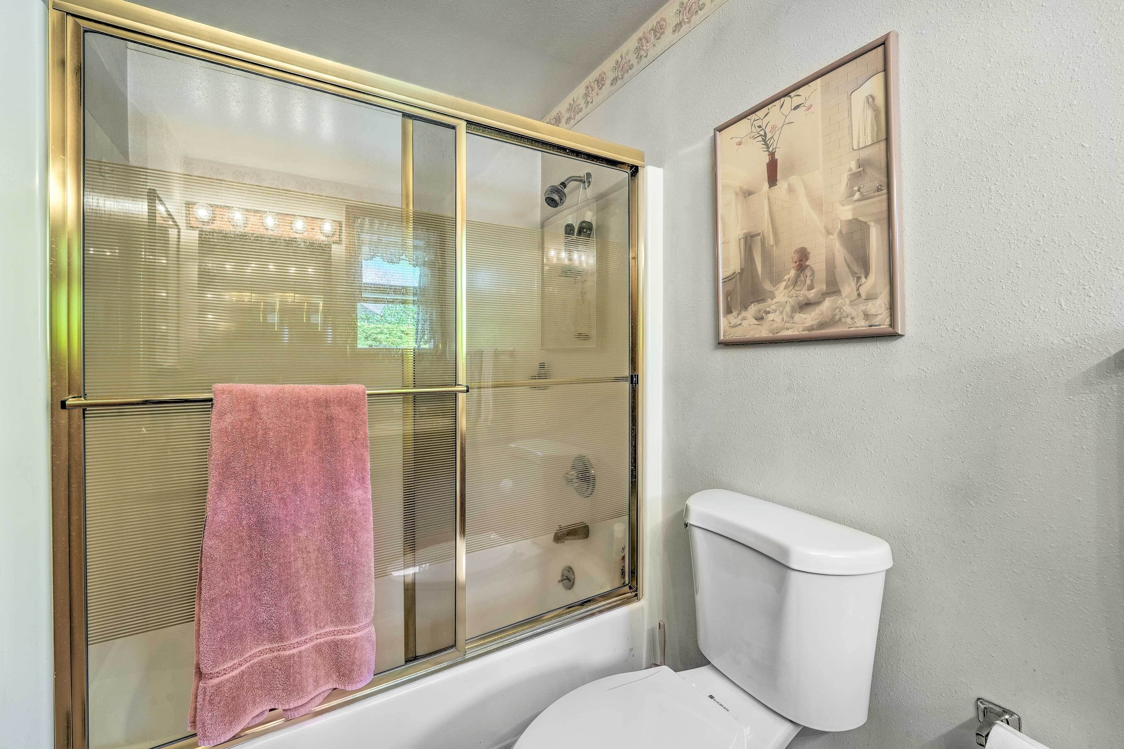 A bathroom with a glass-enclosed shower, a white toilet, and a framed picture on the wall.